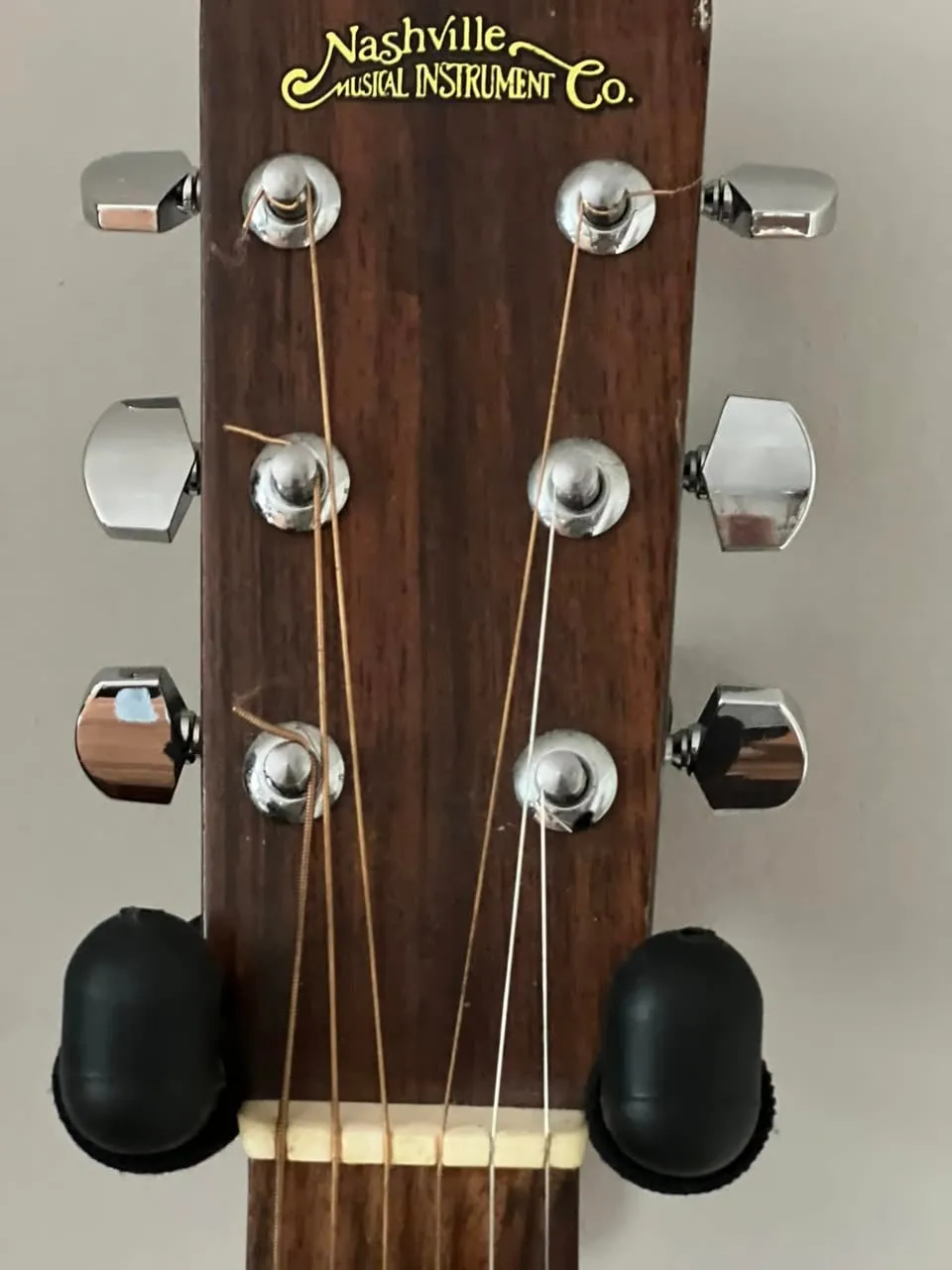 Headstock of a 1970s Nashville Musical Instrument Co. acoustic guitar with the company name in gold script