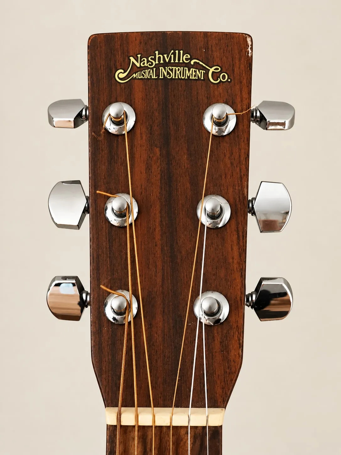 Headstock of a 1970s Nashville Musical Instrument Co. acoustic guitar with the company name in gold script